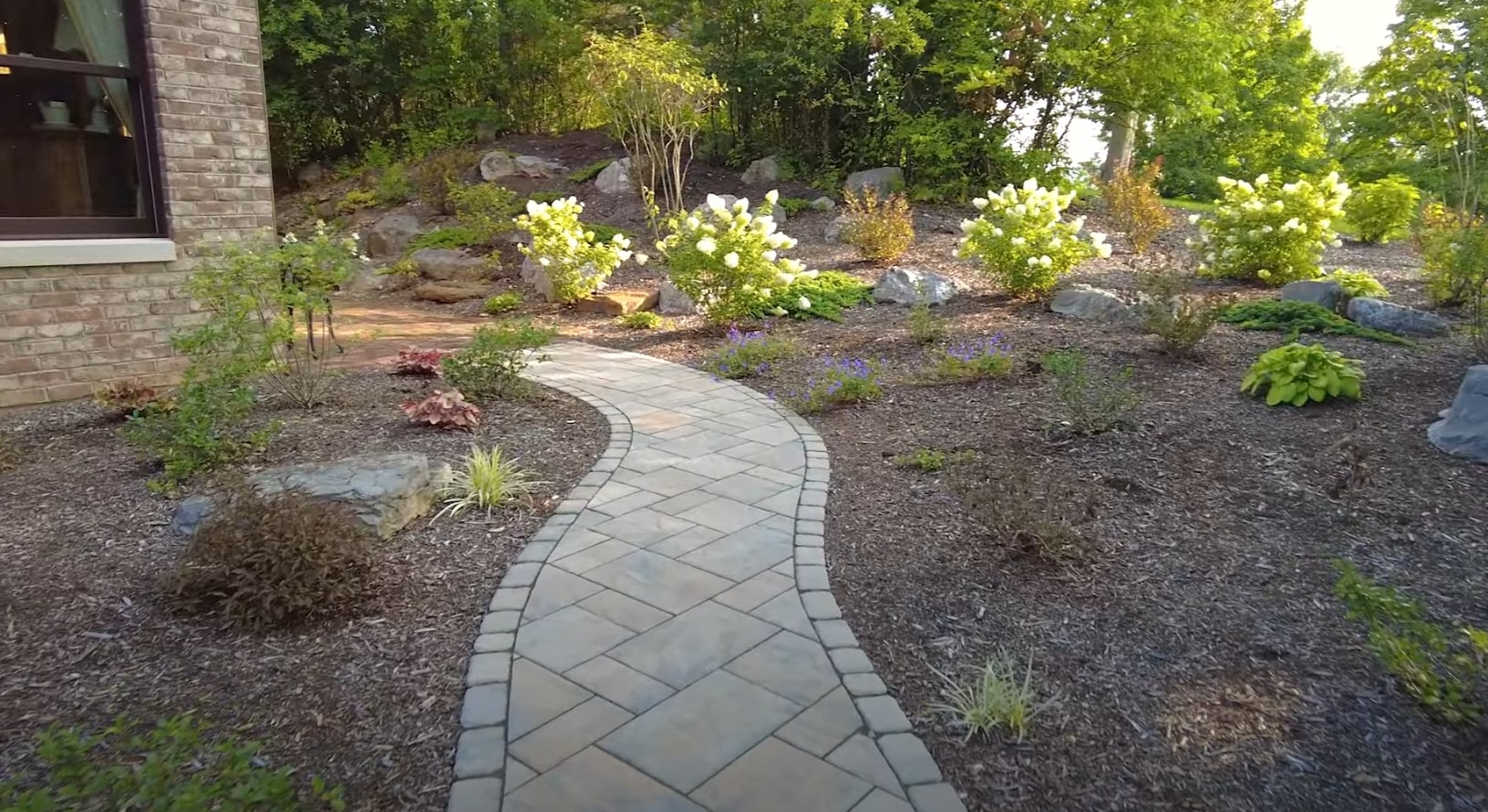 Professional hardscaping with paver walkways and integrated landscape design Hardscape pathway through landscaped garden with decorative stone borders